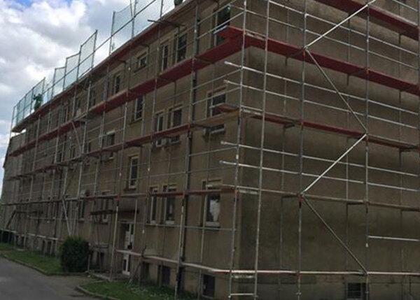 Mehrstöckiges Wohnhaus mit Baugerüst für Fassadensanierung und energetische Modernisierung.